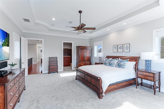 bedroom featuring ceiling fan, light colored carpet, a tray ceiling, and crown molding