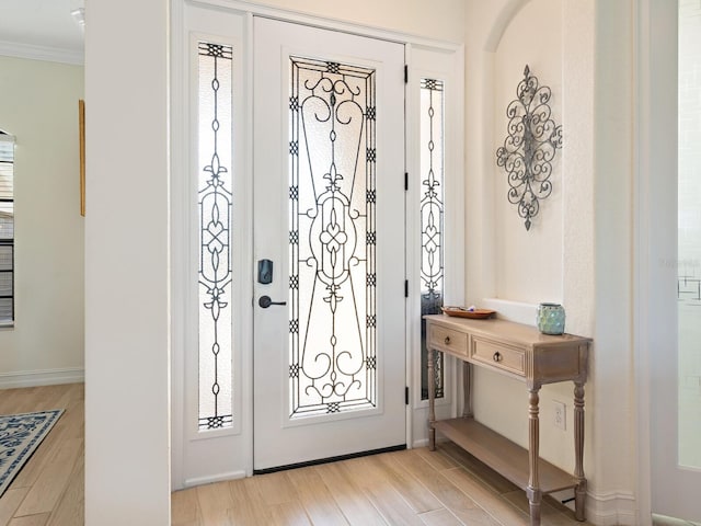 entryway featuring ornamental molding and light hardwood / wood-style flooring