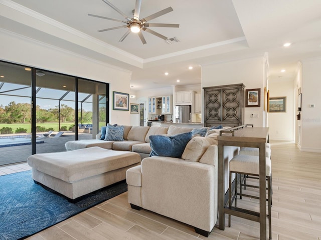 living room with a tray ceiling, ornamental molding, and ceiling fan