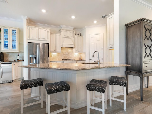 kitchen with sink, stainless steel fridge, a kitchen bar, stainless steel refrigerator with ice dispenser, and light stone countertops