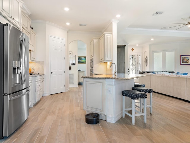 kitchen with a breakfast bar, crown molding, light hardwood / wood-style flooring, stainless steel fridge, and light stone countertops