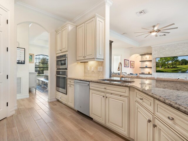 kitchen featuring sink, light wood-type flooring, stainless steel appliances, light stone countertops, and cream cabinets