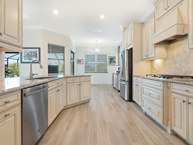 kitchen featuring premium range hood, hanging light fixtures, stainless steel appliances, light stone countertops, and cream cabinetry