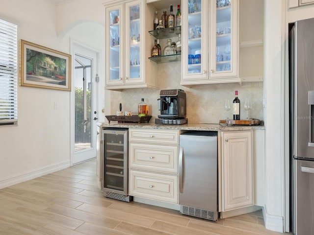 kitchen featuring stainless steel fridge, stainless steel refrigerator, wine cooler, light stone countertops, and decorative backsplash