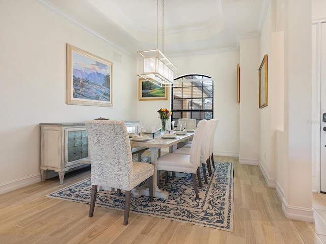 dining area featuring ornamental molding, a tray ceiling, and light hardwood / wood-style floors