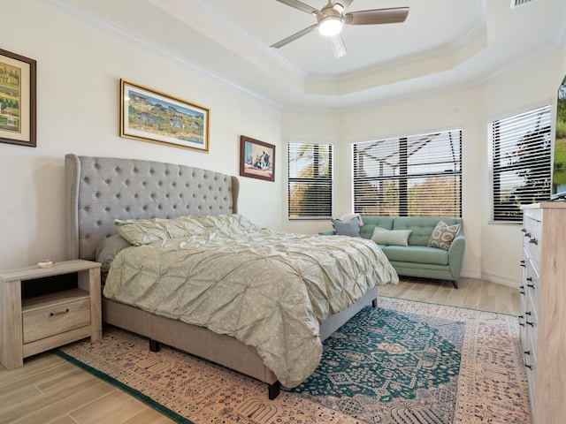 bedroom featuring crown molding, a tray ceiling, and light hardwood / wood-style floors