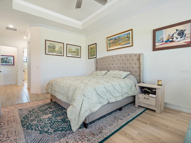 bedroom with a raised ceiling, crown molding, ceiling fan, and light wood-type flooring