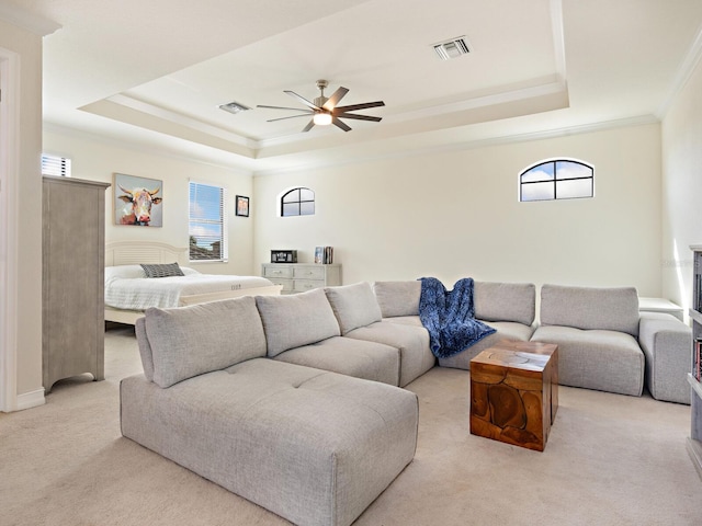 living room featuring crown molding, light colored carpet, a raised ceiling, and a healthy amount of sunlight