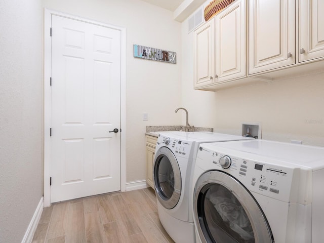 laundry room featuring cabinets, sink, light hardwood / wood-style floors, and washing machine and dryer