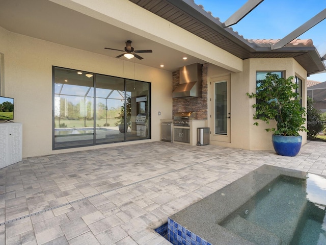 view of patio featuring ceiling fan, area for grilling, exterior kitchen, and glass enclosure