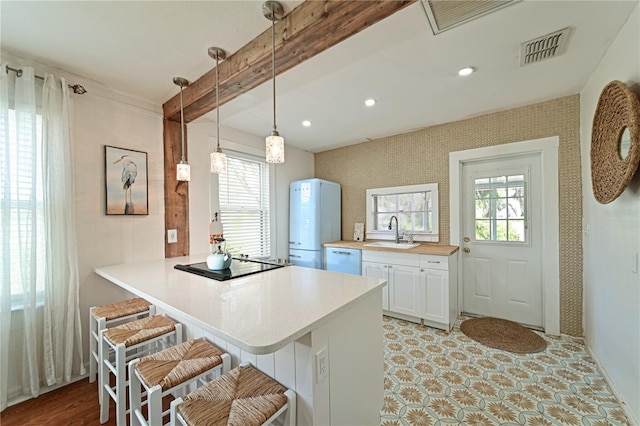 kitchen featuring dishwasher, white cabinetry, sink, a kitchen bar, and hanging light fixtures