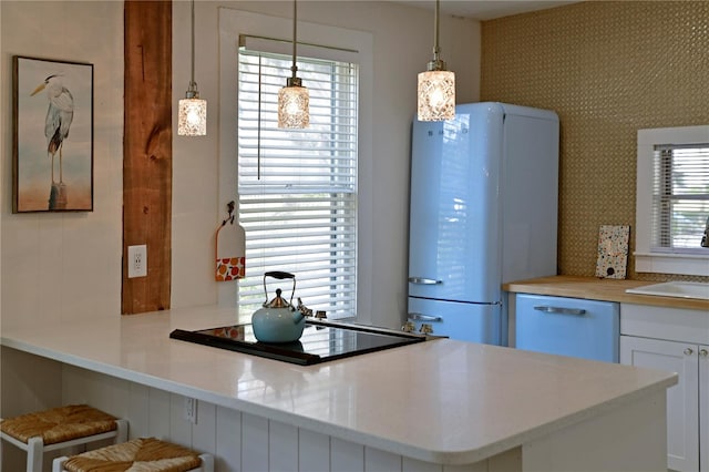 kitchen with decorative light fixtures, dishwasher, white cabinets, white fridge, and kitchen peninsula