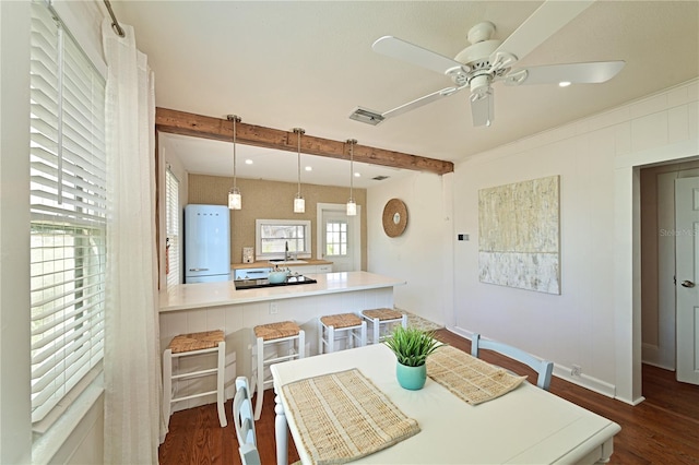 dining room with ceiling fan, dark hardwood / wood-style floors, sink, and beam ceiling