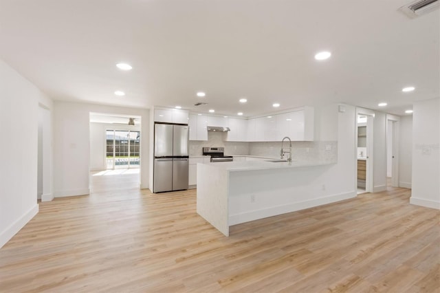 kitchen with white cabinetry, kitchen peninsula, stainless steel appliances, and light hardwood / wood-style flooring