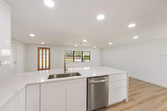 kitchen featuring sink, stainless steel dishwasher, light stone countertops, white cabinetry, and light wood-type flooring