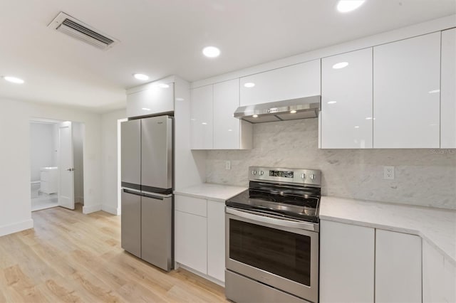 kitchen featuring stainless steel appliances, light hardwood / wood-style floors, tasteful backsplash, extractor fan, and white cabinetry