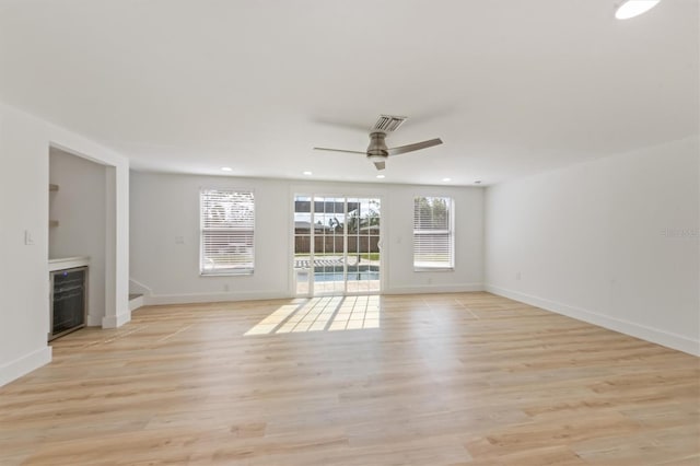 unfurnished living room featuring ceiling fan, beverage cooler, and light hardwood / wood-style floors