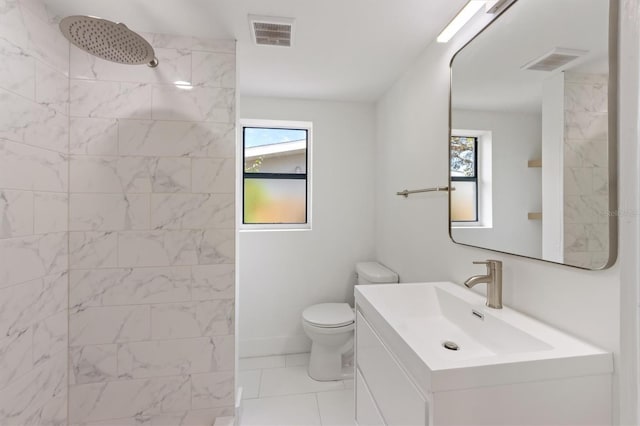 bathroom featuring tile patterned flooring, tiled shower, toilet, and vanity