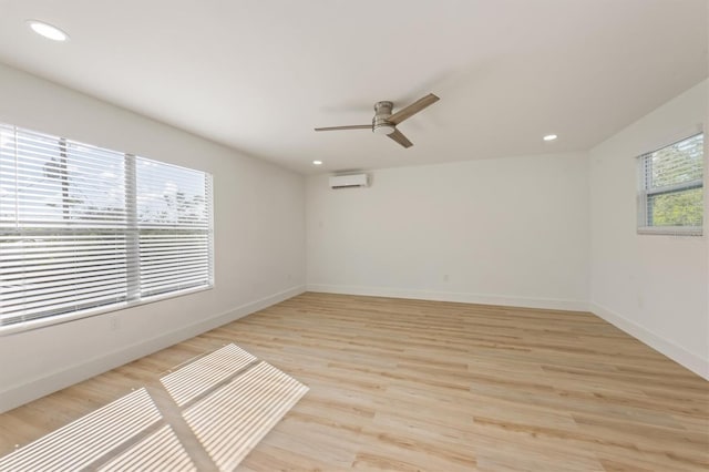 unfurnished room with ceiling fan, a wall mounted air conditioner, and light hardwood / wood-style floors