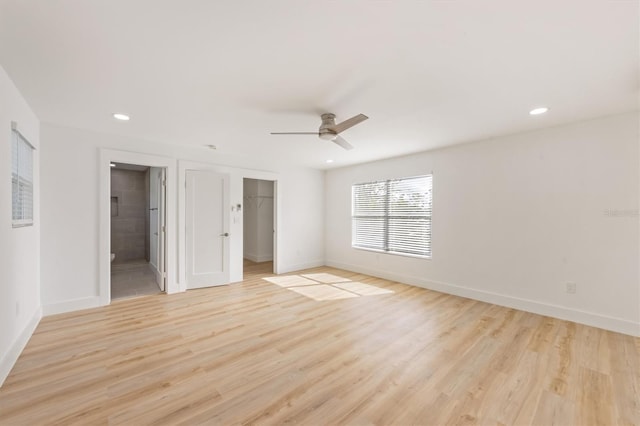 unfurnished bedroom featuring a closet, a spacious closet, connected bathroom, ceiling fan, and light hardwood / wood-style flooring