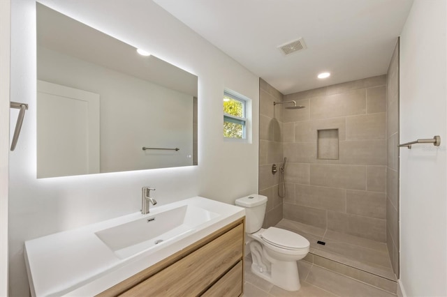 bathroom featuring toilet, vanity, tile patterned floors, and a tile shower