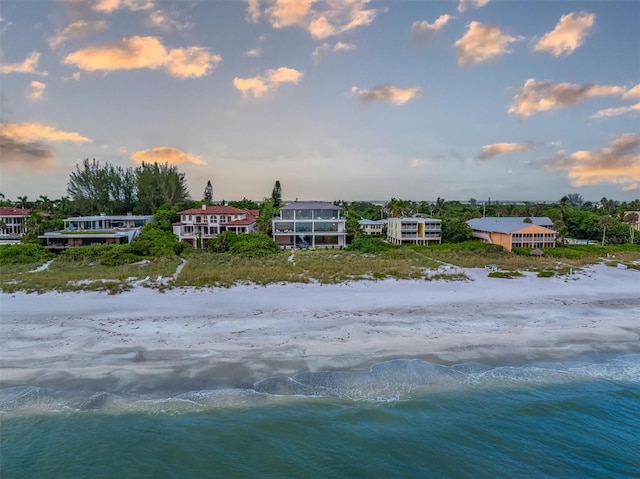 aerial view at dusk featuring a beach view and a water view