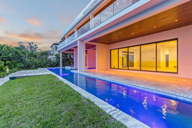 pool at dusk featuring a yard and a patio area