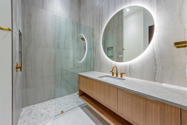 bathroom with vanity, tile patterned floors, a tile shower, and tile walls