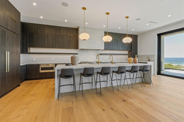 kitchen with light wood-type flooring, decorative light fixtures, and a breakfast bar