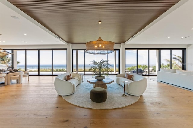 living room featuring a water view, floor to ceiling windows, and light hardwood / wood-style flooring