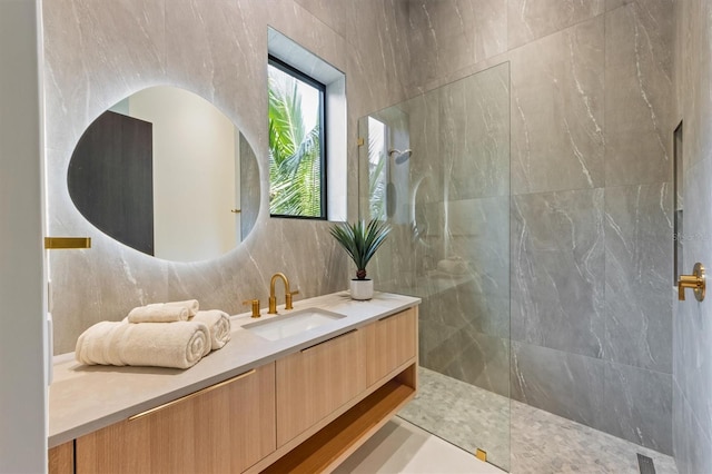 bathroom with tile walls, vanity, and tiled shower