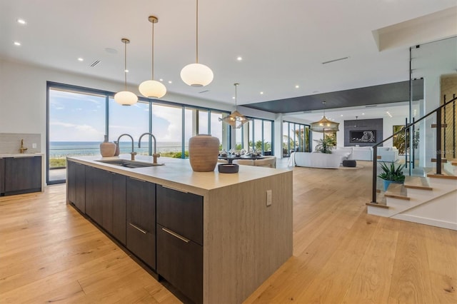 kitchen featuring a water view, sink, a large island, light hardwood / wood-style flooring, and decorative light fixtures