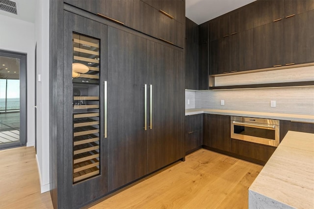 kitchen featuring dark brown cabinetry, light hardwood / wood-style floors, and stainless steel oven