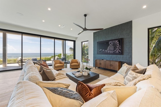 living room with a wealth of natural light, ceiling fan, a water view, and light hardwood / wood-style floors