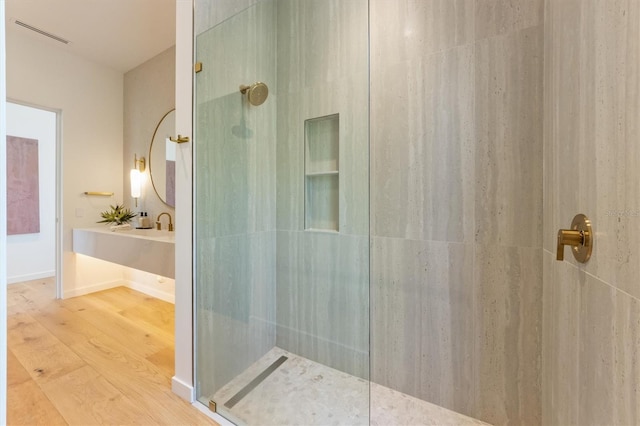 bathroom with hardwood / wood-style flooring, vanity, and a tile shower