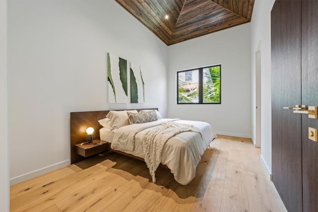 bedroom with wooden ceiling, light wood-type flooring, and high vaulted ceiling