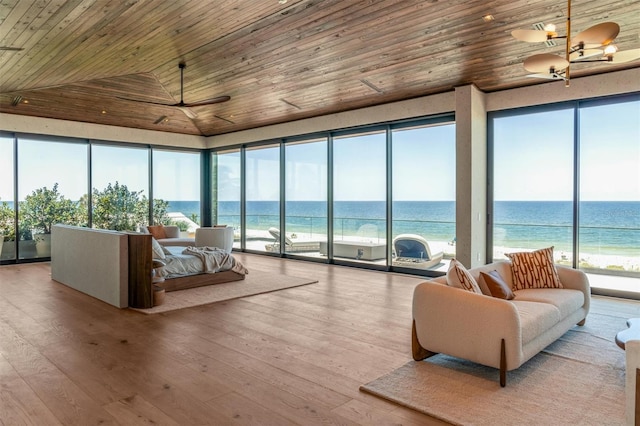 sunroom / solarium featuring plenty of natural light, a view of the beach, a water view, and lofted ceiling