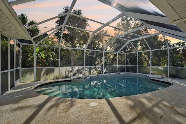 pool at dusk with a patio area and a lanai