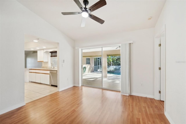 unfurnished living room featuring ceiling fan, sink, light wood-type flooring, and vaulted ceiling