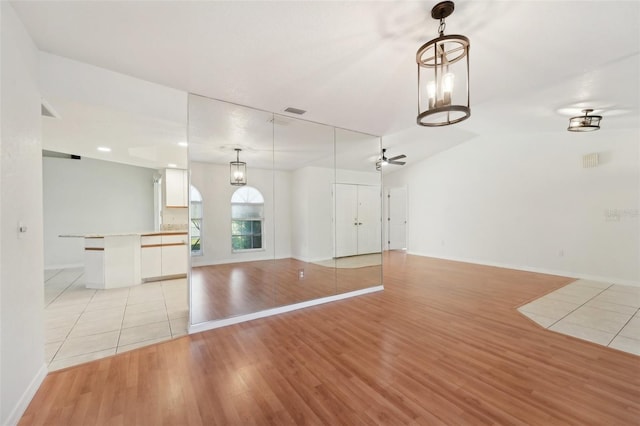 unfurnished living room with light wood-type flooring, vaulted ceiling, and ceiling fan