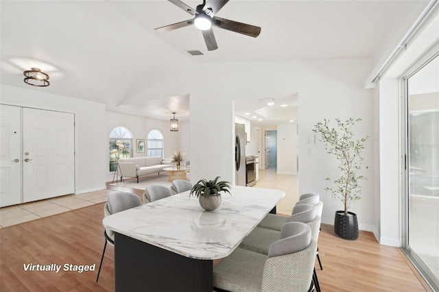 dining space featuring light hardwood / wood-style floors, ceiling fan, and vaulted ceiling