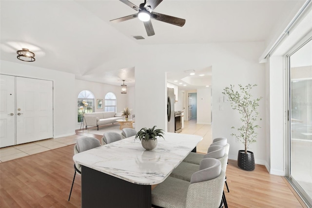 dining area featuring ceiling fan, vaulted ceiling, and light hardwood / wood-style floors