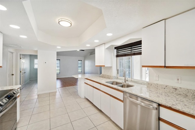 kitchen with white cabinetry, sink, light stone counters, appliances with stainless steel finishes, and a tray ceiling