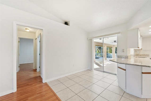 kitchen featuring white cabinetry, sink, light stone countertops, ceiling fan, and light hardwood / wood-style flooring