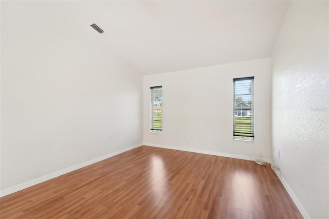 unfurnished room with hardwood / wood-style flooring and vaulted ceiling