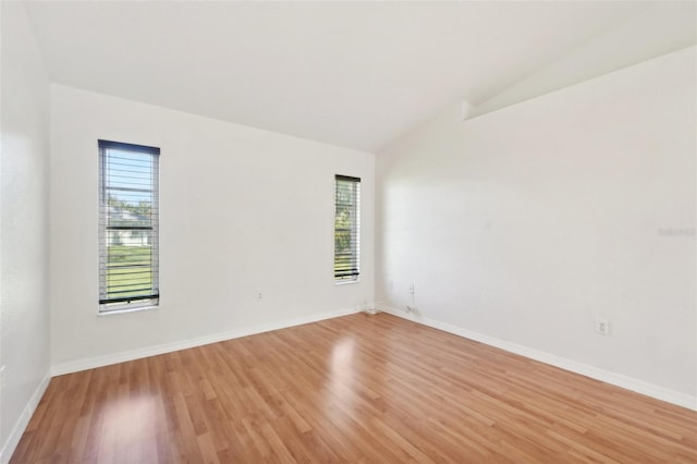 spare room featuring vaulted ceiling and light hardwood / wood-style floors