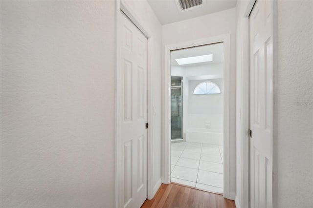 corridor featuring hardwood / wood-style floors and a skylight