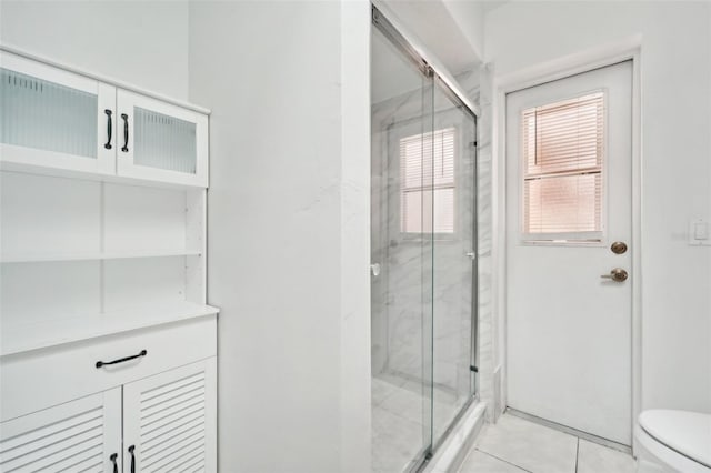 bathroom featuring a shower with shower door, tile patterned flooring, and toilet