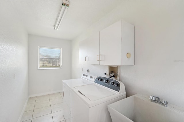 laundry area with light tile patterned floors, cabinets, sink, and washing machine and clothes dryer