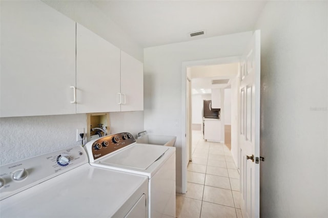 laundry area with sink, cabinets, washing machine and clothes dryer, and light tile patterned flooring